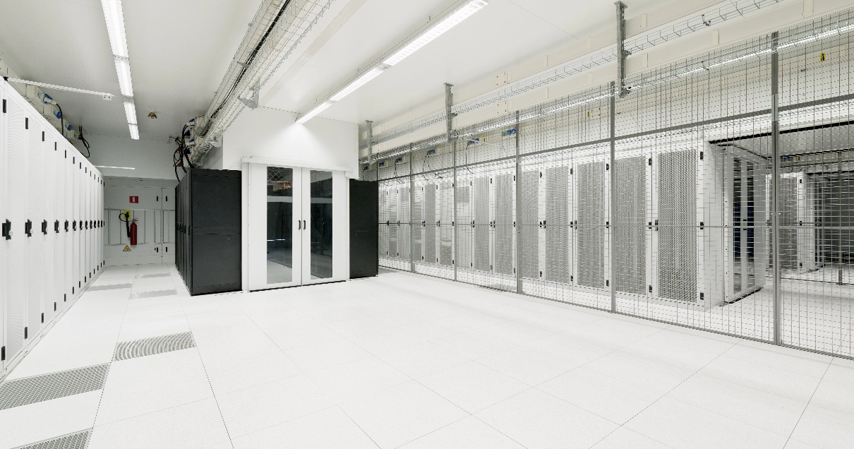 Pristine white datacenter with lots of open space and server racks behind locked cages.